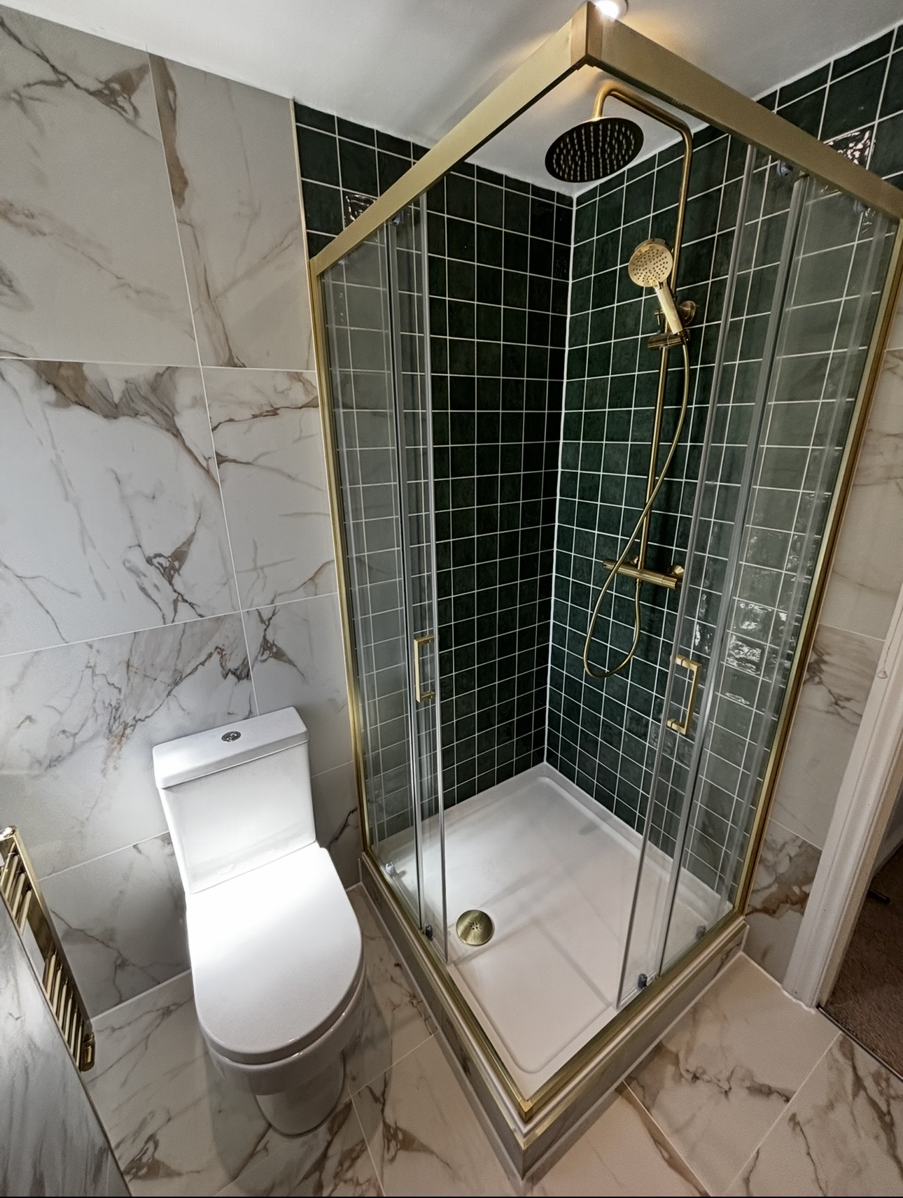 Corner shower enclosure with green metro tiles, marble walls and brushed brass frame in a Stourbridge bathroom by M3 Trades