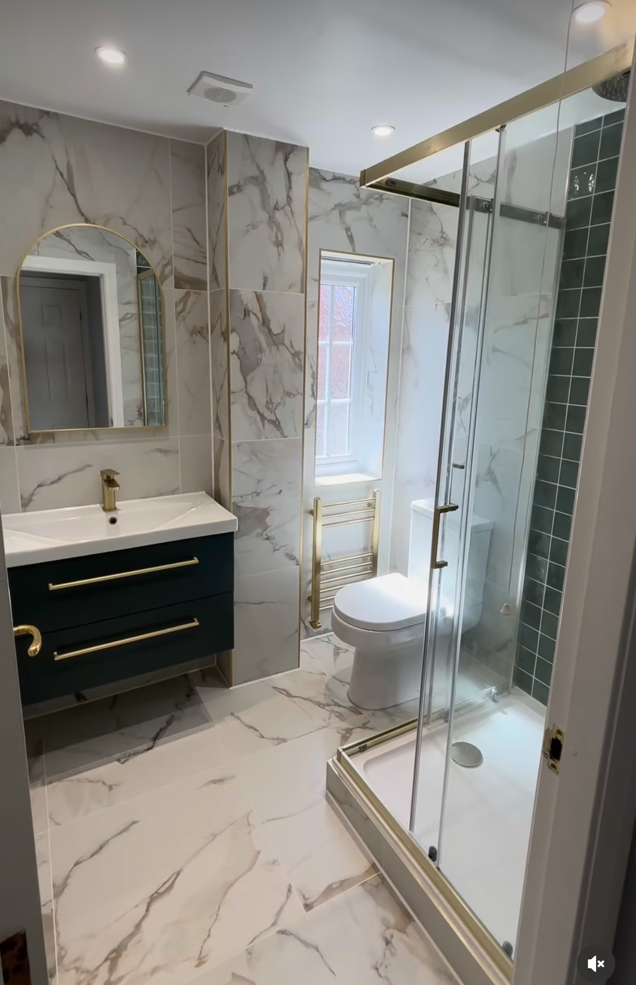 Marble-tiled bathroom with navy vanity unit, brushed brass fittings and walk-in shower in Stourbridge by M3 Trades