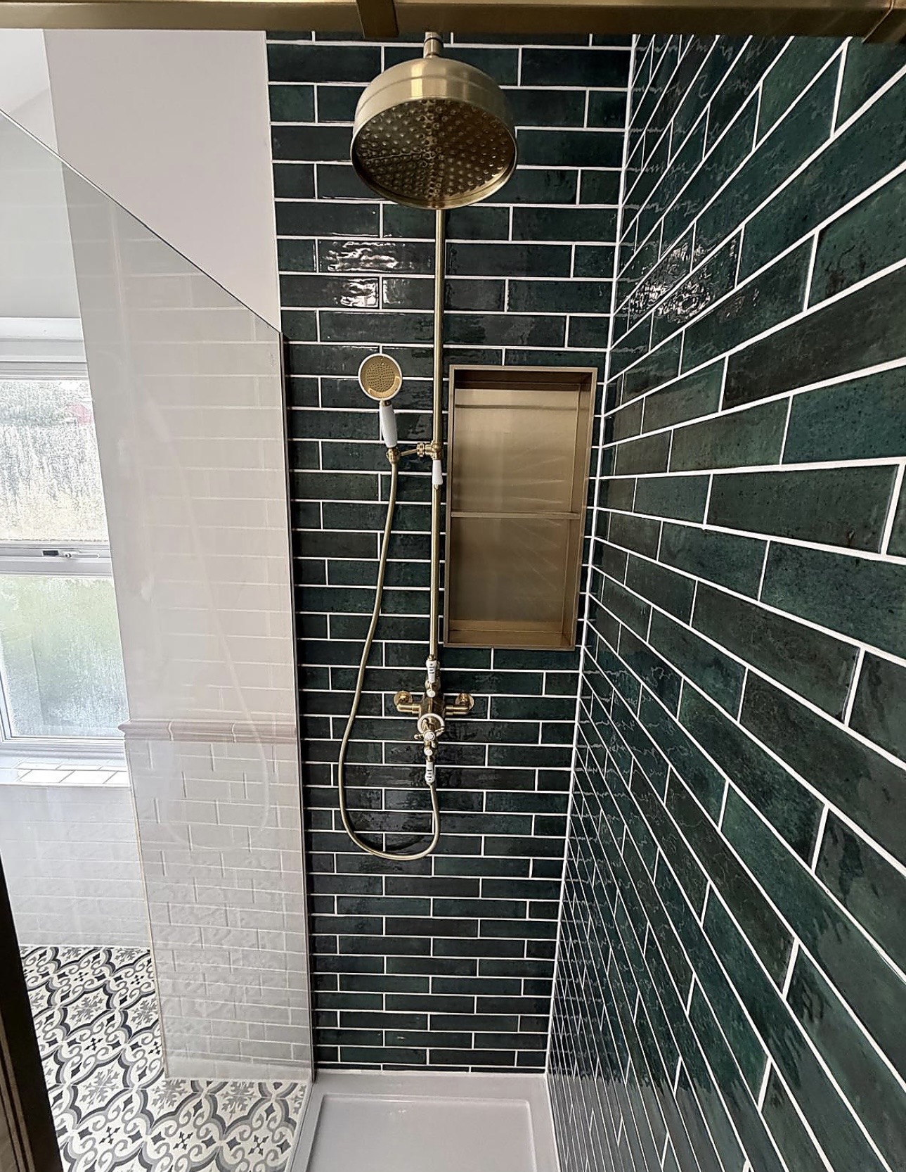 Brushed brass rainfall shower and recessed niche set against dark green metro tiles in a completed B67 bathroom by M3 Trades